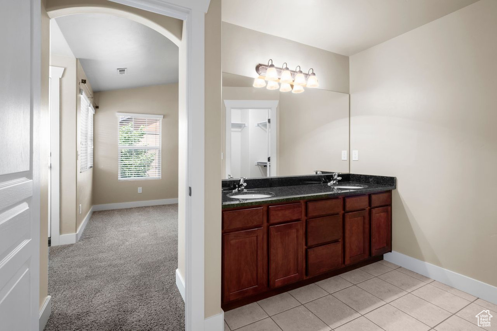 Full bath with double vanity, vaulted ceiling, and tile patterned flooring