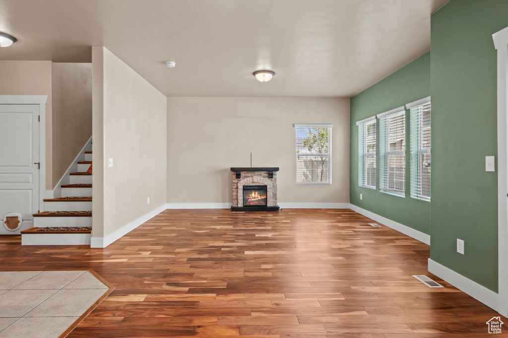 Unfurnished living room with wood finished floors, a fireplace, and stairs