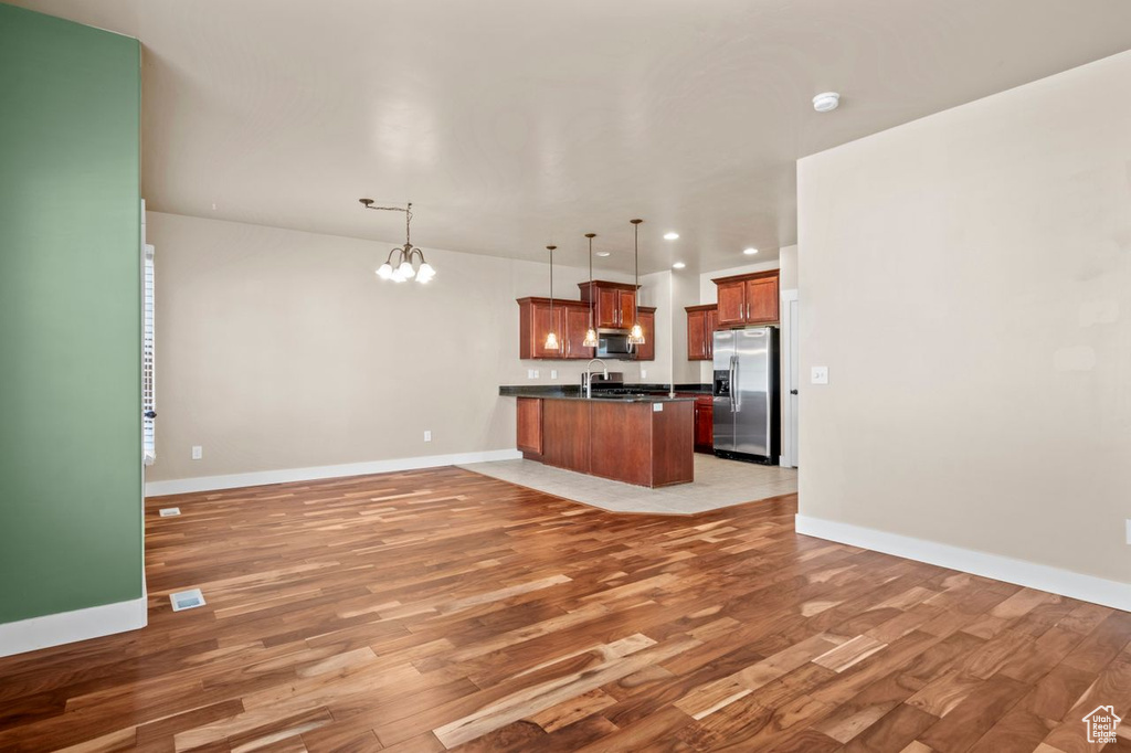 Unfurnished living room featuring a chandelier, light wood finished floors, and recessed lighting
