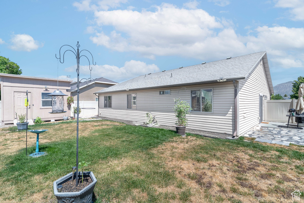 Back of house featuring a patio and roof with shingles