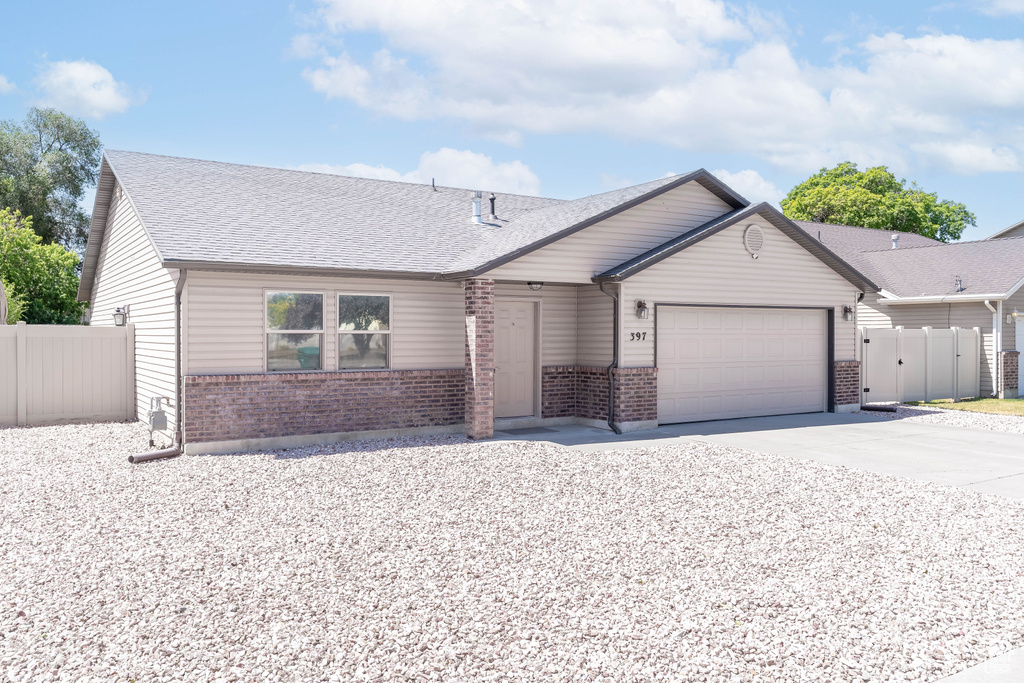 View of front of home with brick siding, a garage, driveway, and a shingled roof
