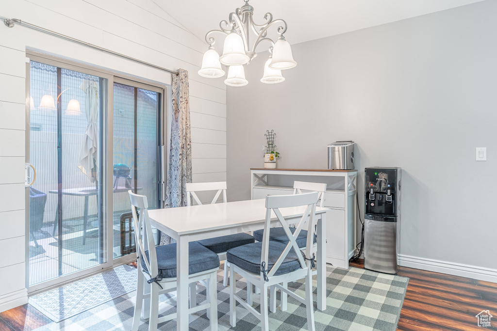 Dining area featuring wood finished floors, a chandelier, and wood walls