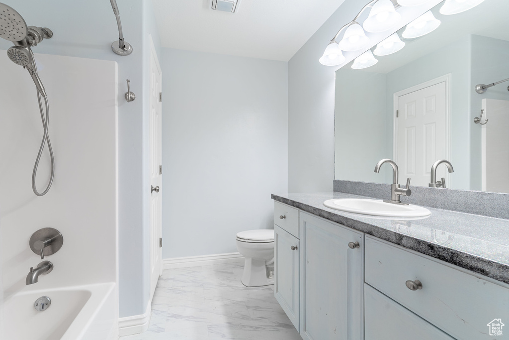 Bathroom with marble finish floors, washtub / shower combination, and vanity