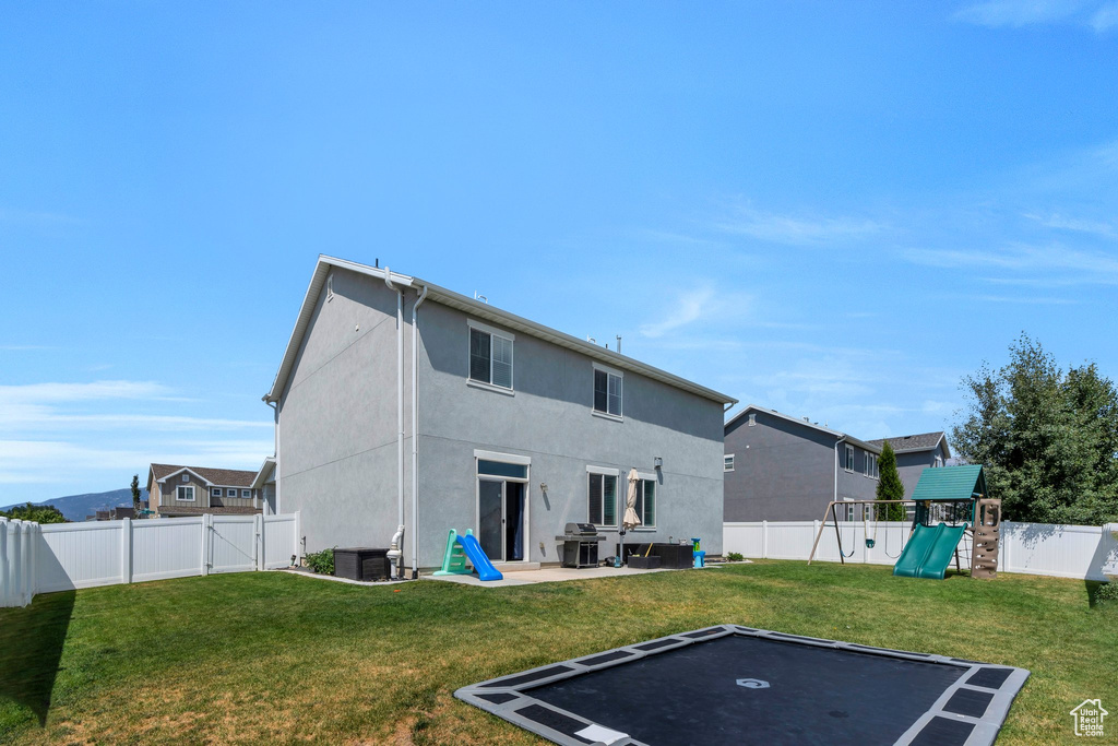 Rear view of property with a fenced backyard, a playground, a gate, and stucco siding
