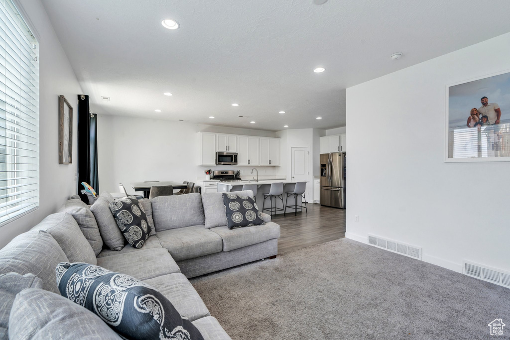 Living room featuring recessed lighting, dark colored carpet, and healthy amount of natural light
