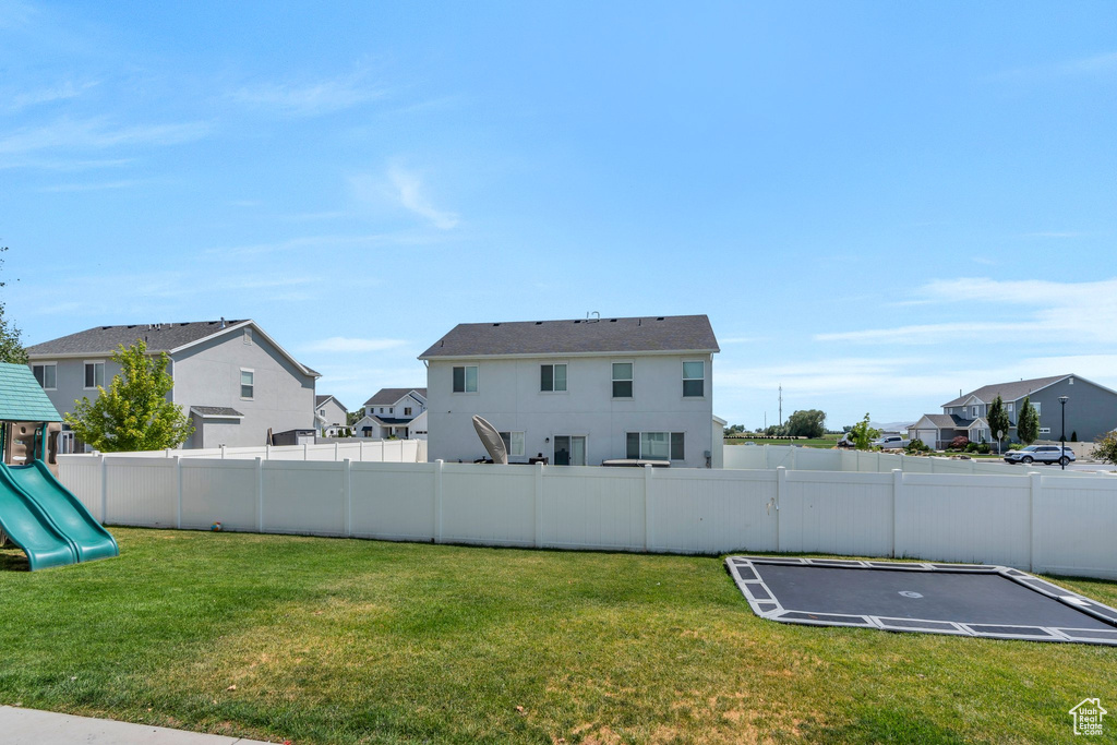 Fenced backyard featuring a residential view, a playground, and a trampoline