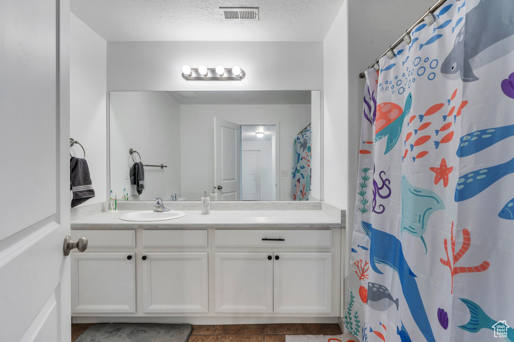 Full bathroom featuring vanity, a textured ceiling, and a shower with curtain