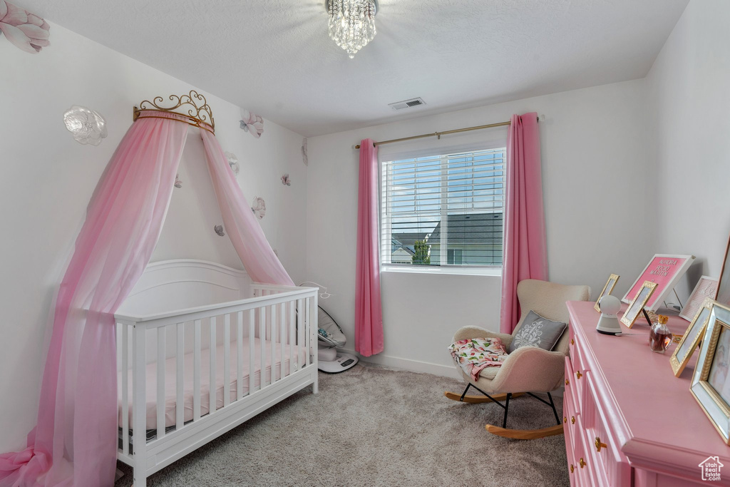 Bedroom featuring a nursery area and carpet flooring