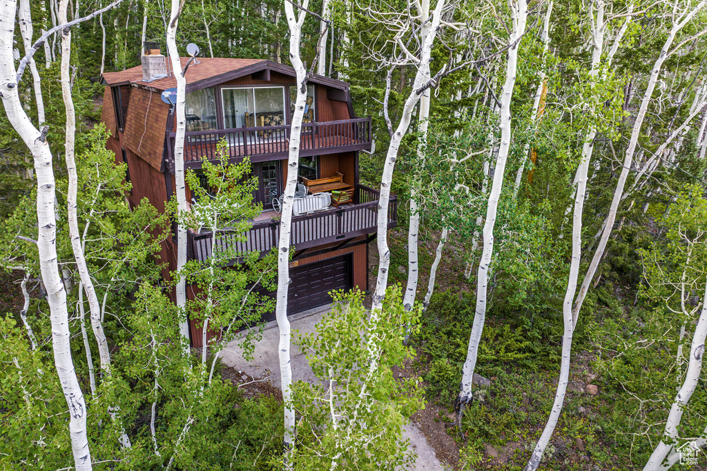 Back of property with driveway, an attached garage, and a wooden deck