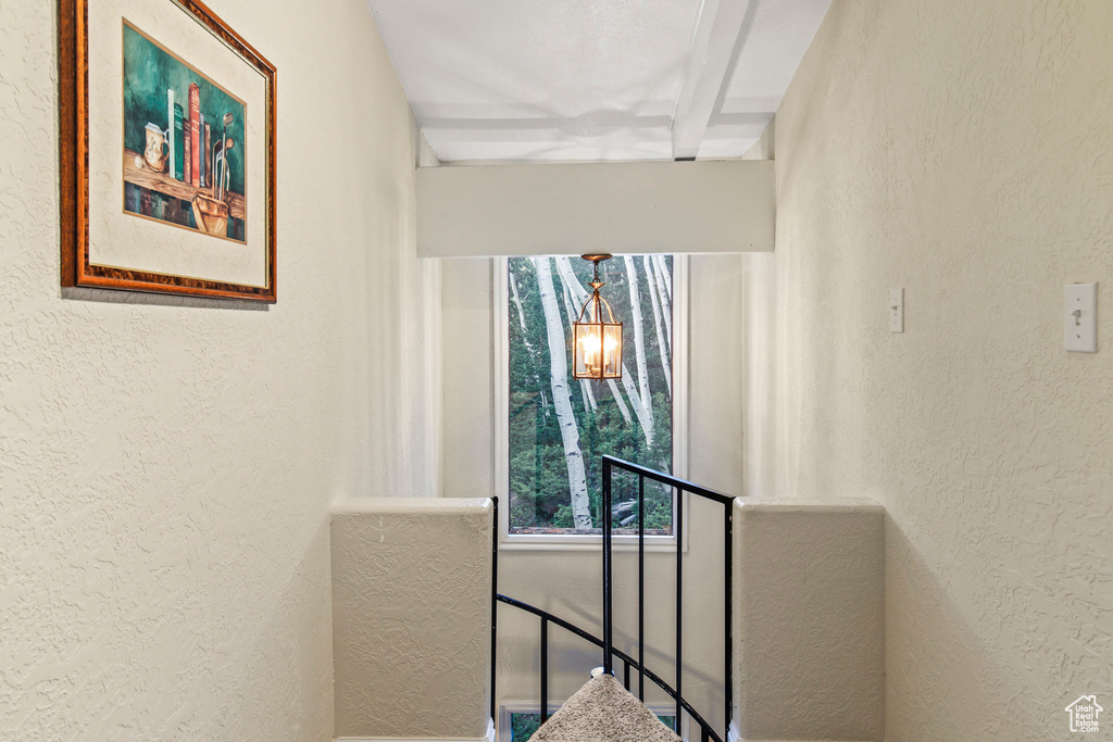 Corridor with a textured wall and an upstairs landing