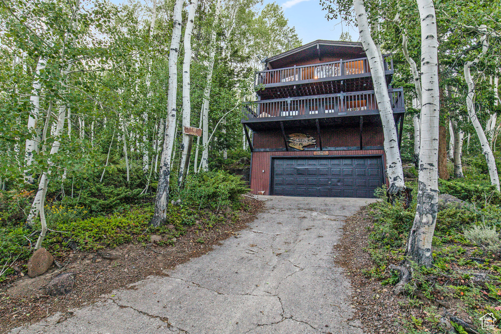 View of front facade featuring driveway, a garage, and a deck