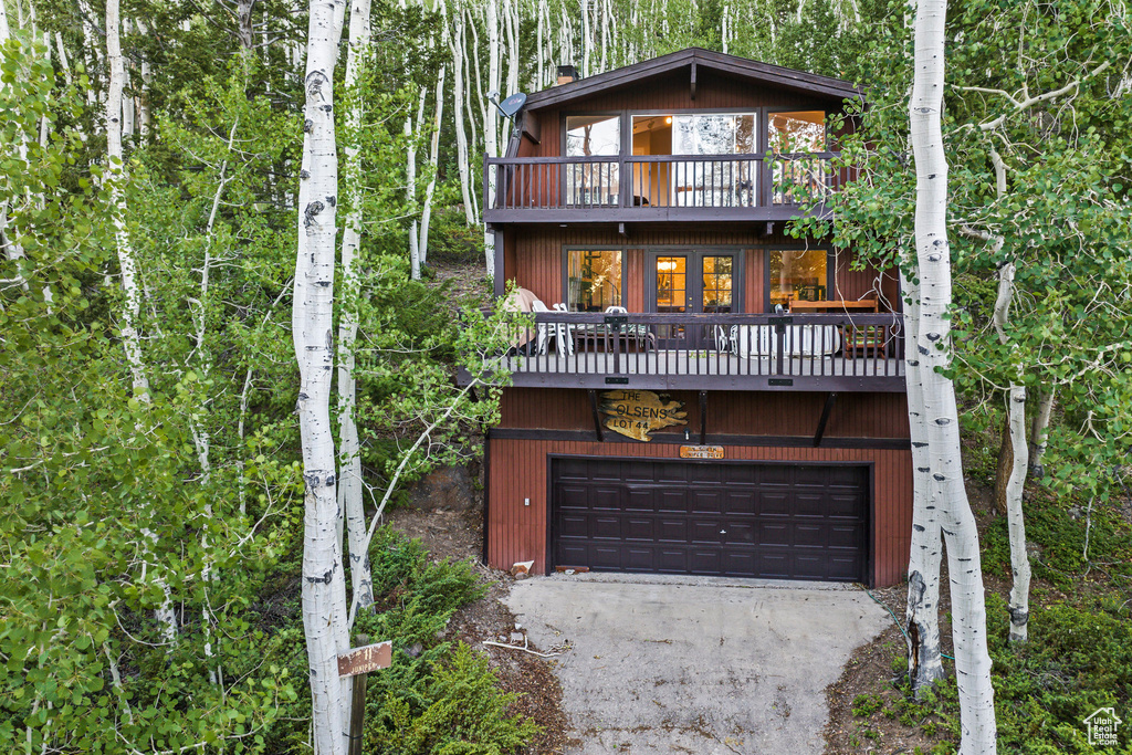 Chalet / cabin featuring an attached garage, a balcony, and driveway