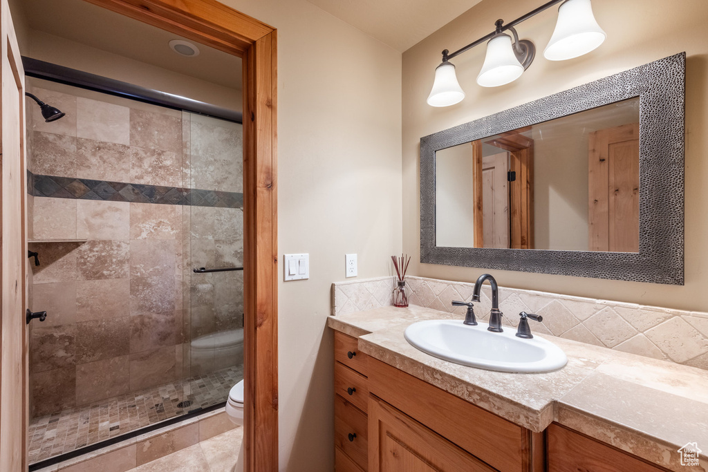 Full bathroom featuring a stall shower, vanity, and tasteful backsplash