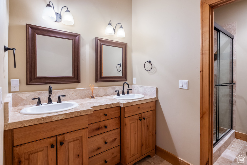 Bathroom featuring a shower stall and double vanity