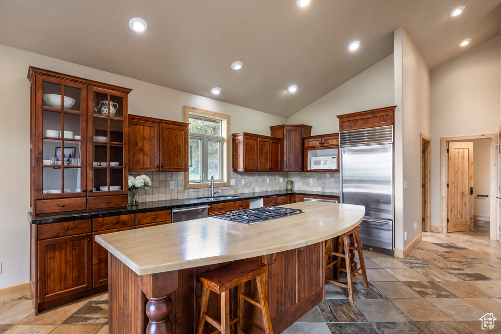 Kitchen featuring stainless steel appliances, a kitchen breakfast bar, wooden counters, decorative backsplash, and a center island