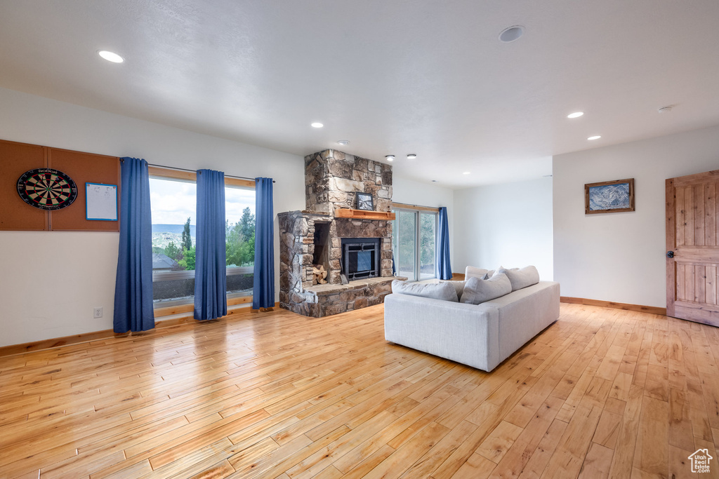 Living area featuring light wood finished floors, a stone fireplace, recessed lighting, and plenty of natural light