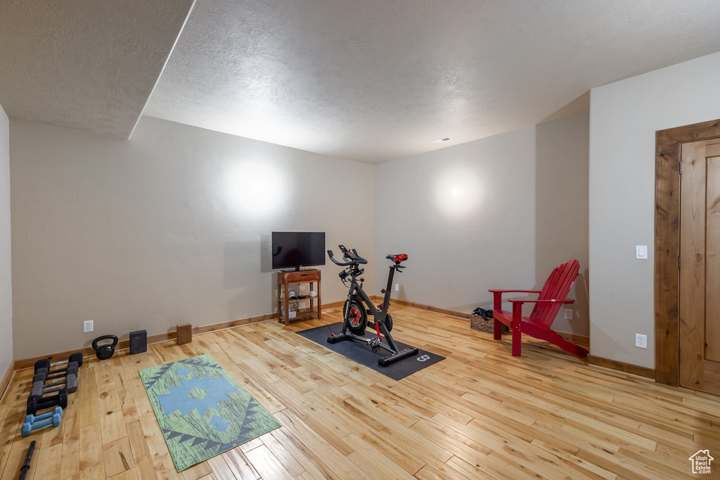Exercise room with hardwood / wood-style flooring and a textured ceiling