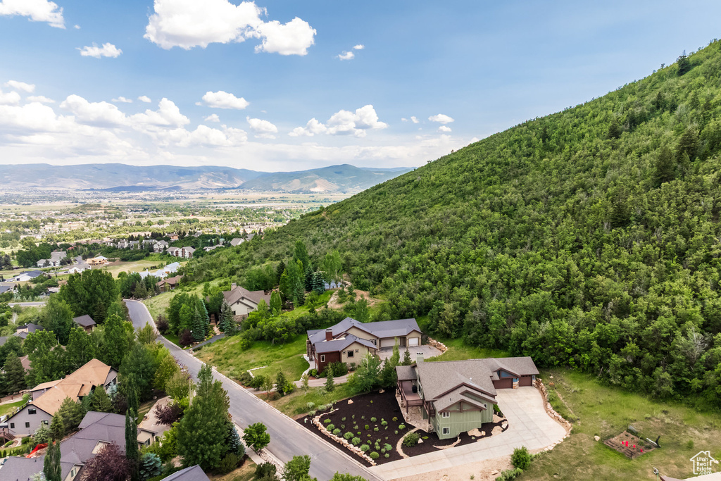 Aerial view of property and surrounding area with a mountainous background and a heavily wooded area