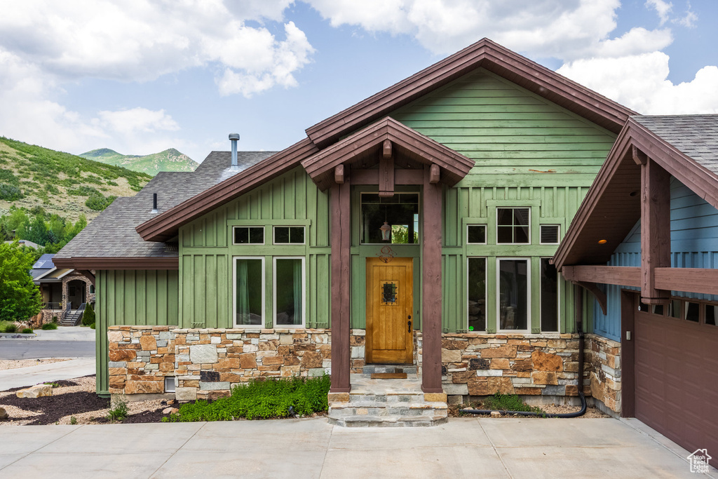 View of front of house with board and batten siding, stone siding, roof with shingles, and a mountain view