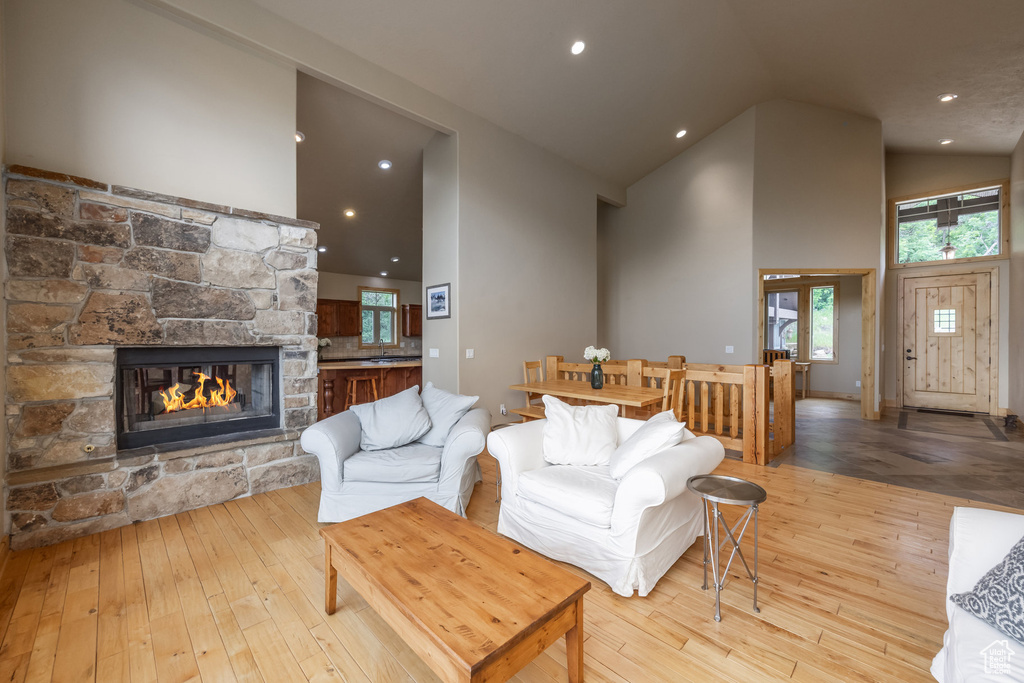 Living room featuring high vaulted ceiling, a fireplace, hardwood / wood-style flooring, and recessed lighting