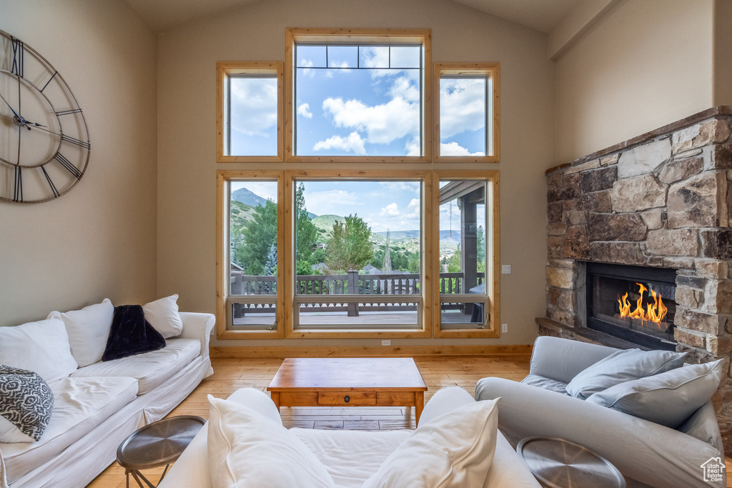Living area featuring healthy amount of natural light, a fireplace, wood finished floors, and high vaulted ceiling