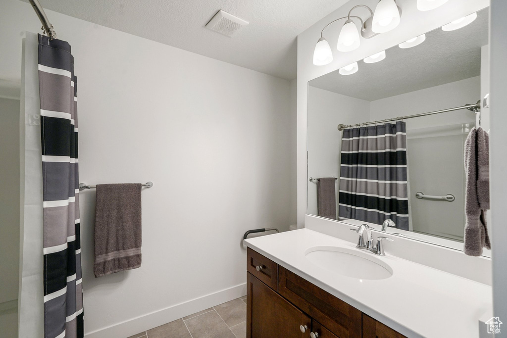 Full bathroom featuring vanity, tile patterned floors, and a shower with curtain