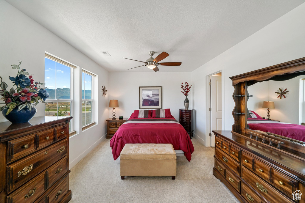 Bedroom with light carpet, a ceiling fan, and a textured ceiling