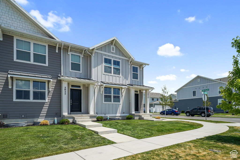 View of front of house with board and batten siding, a front lawn, and a residential view