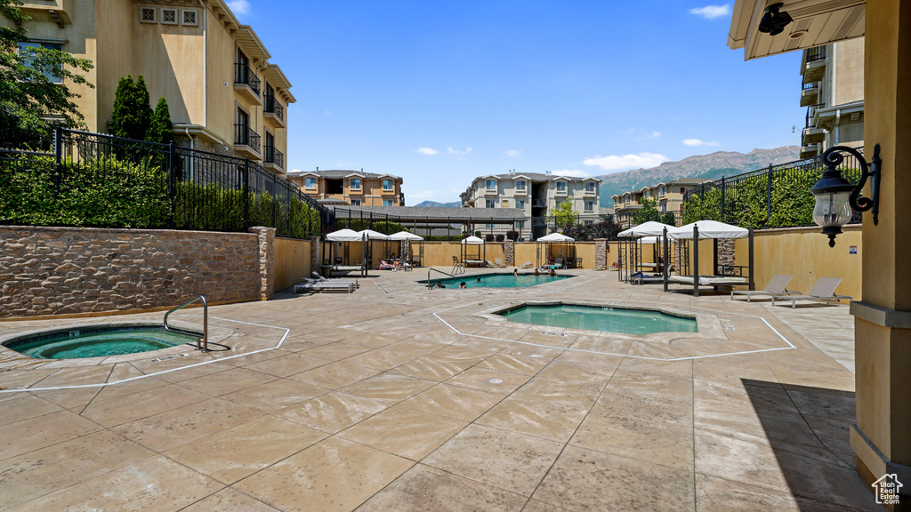 Community pool with a community hot tub, a patio, a fenced backyard, and a mountain view