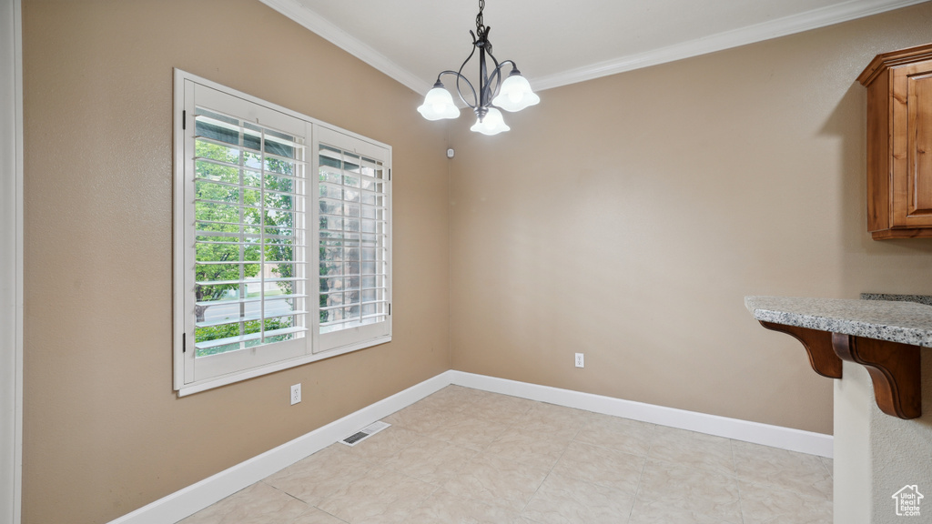Unfurnished dining area featuring healthy amount of natural light, crown molding, and a chandelier