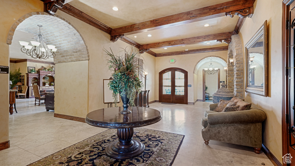 Foyer with a chandelier, arched walkways, beamed ceiling, ornamental molding, and recessed lighting