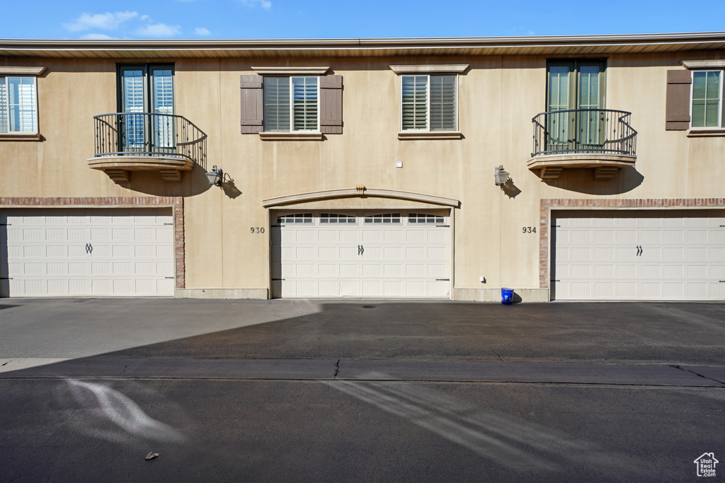 View of front of property featuring a balcony, an attached garage, and driveway