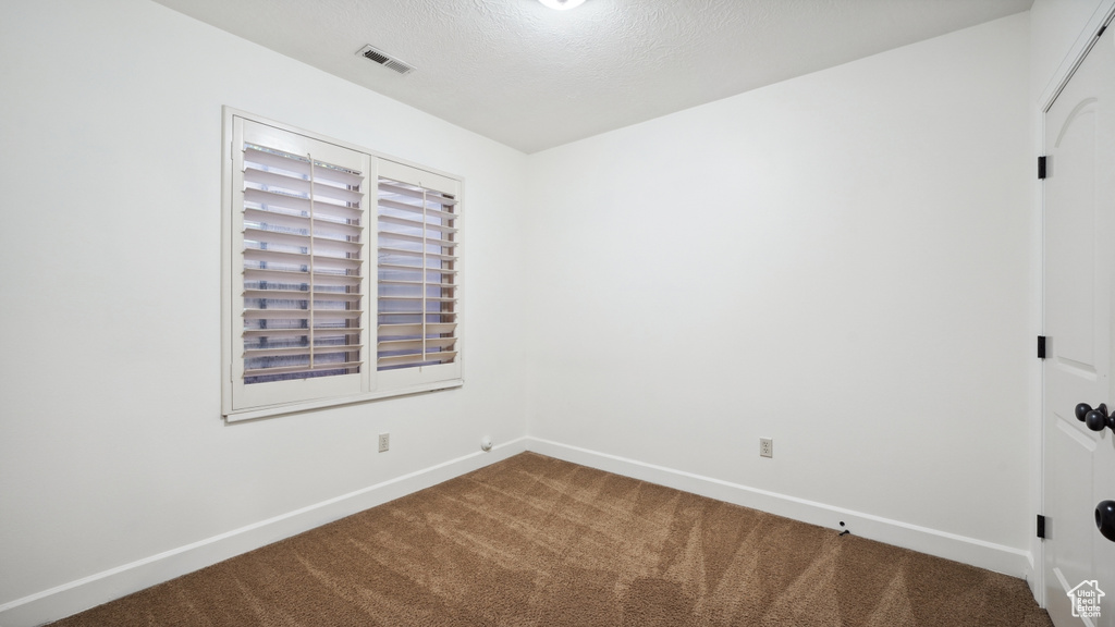 Carpeted empty room with baseboards and a textured ceiling