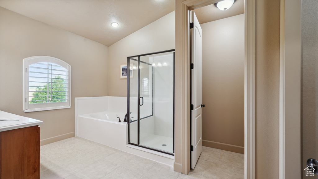 Full bath with a bath, a stall shower, vanity, and lofted ceiling
