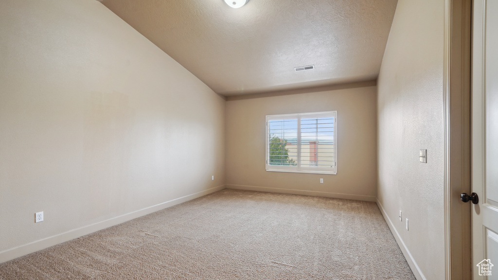 Carpeted empty room with a textured ceiling and baseboards