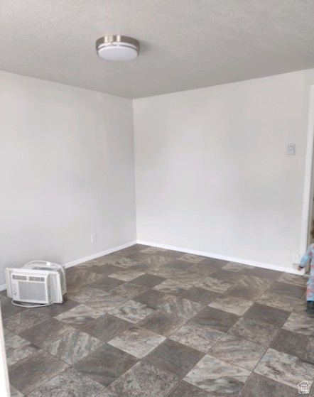 Empty room featuring baseboards and an AC wall unit