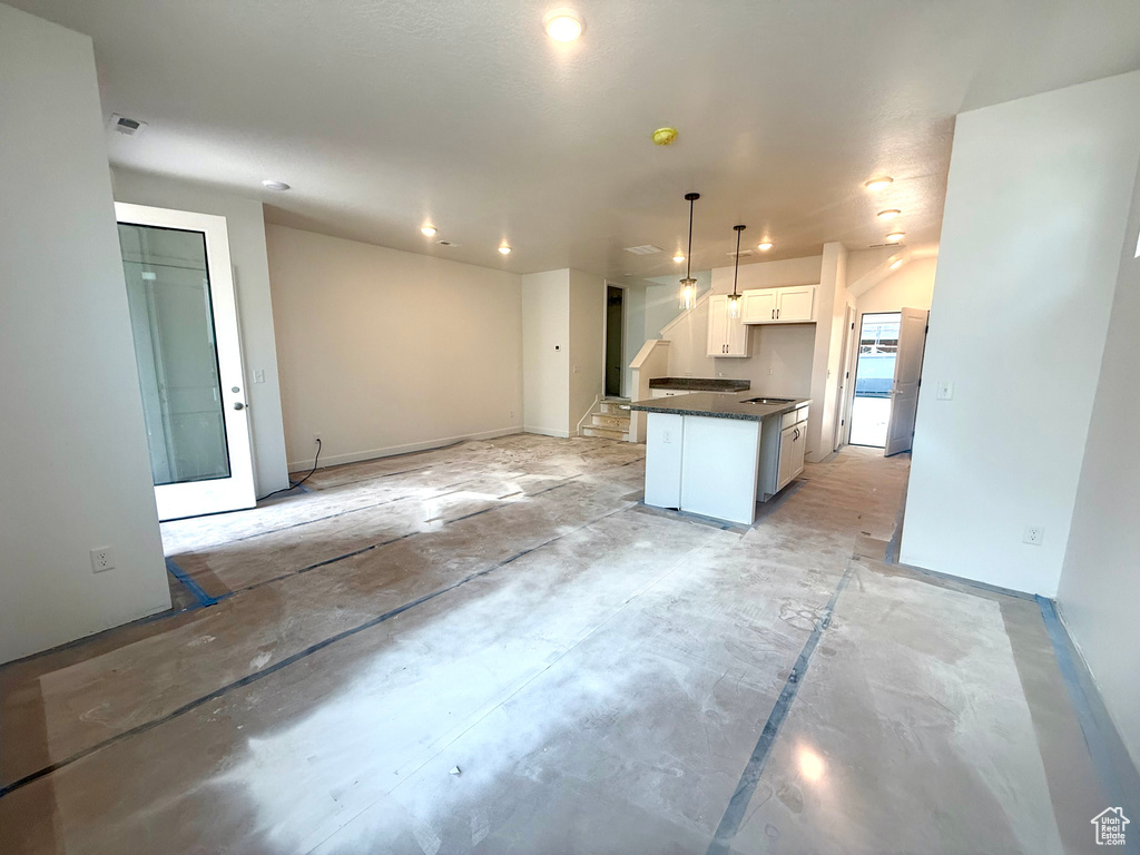 Kitchen with dark countertops, white cabinetry, hanging light fixtures, open floor plan, and recessed lighting