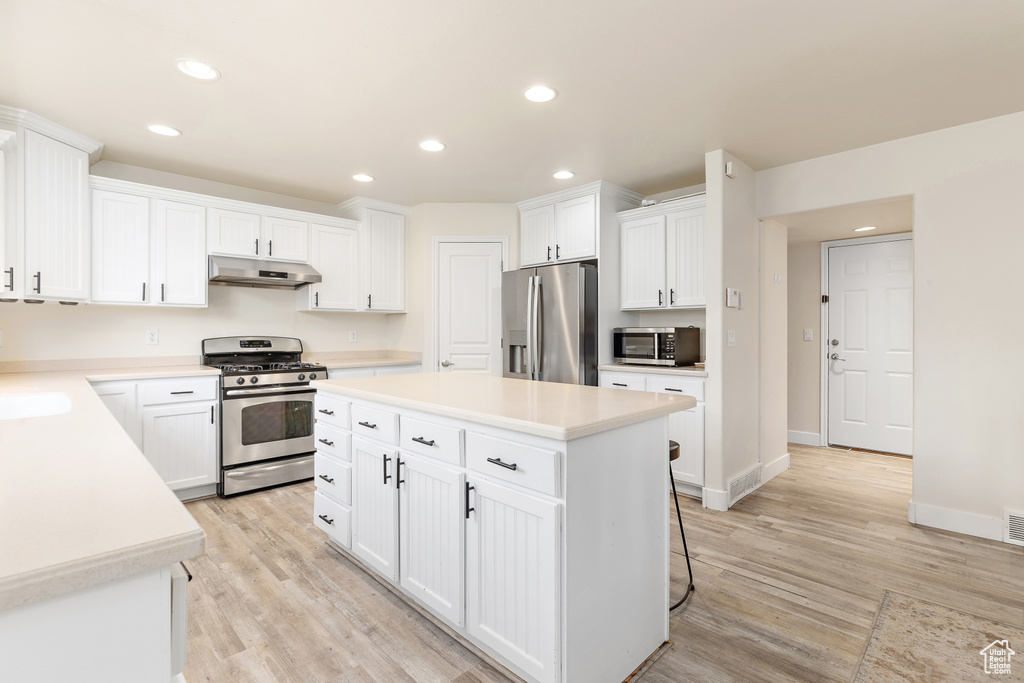 Kitchen with appliances with stainless steel finishes, under cabinet range hood, recessed lighting, light wood-style flooring, and light countertops