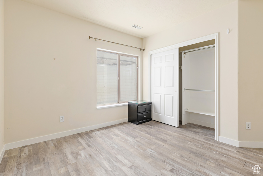 Unfurnished bedroom featuring light wood-style flooring and a closet