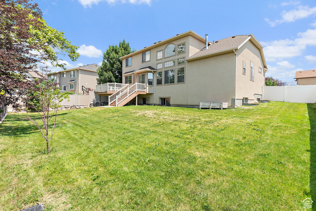 Rear view of house featuring stairs, a fenced backyard, a wooden deck, and stucco siding