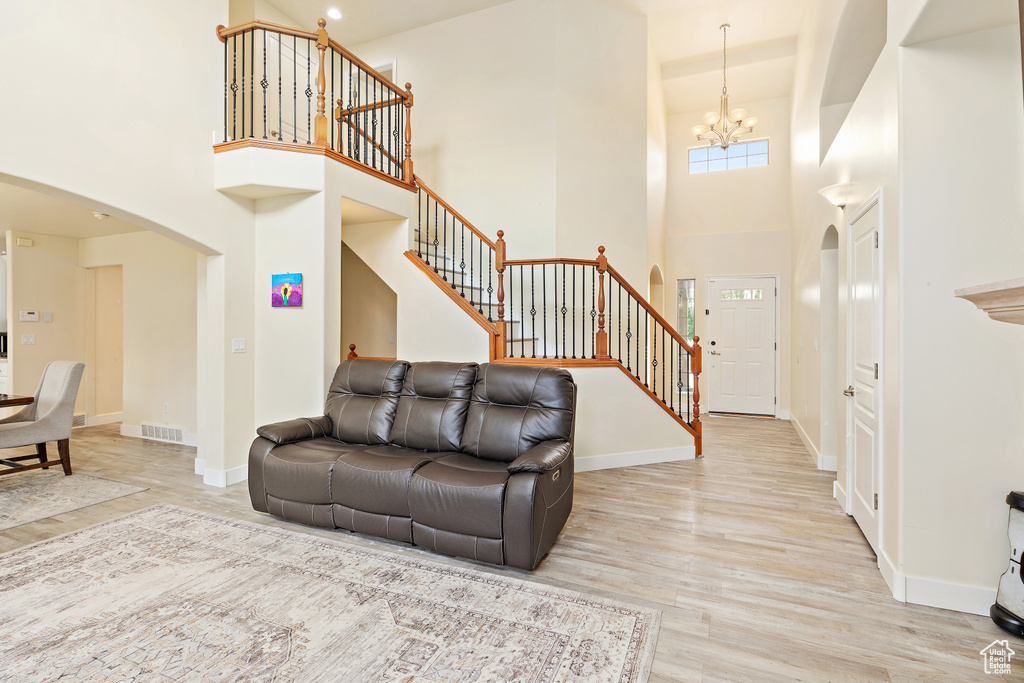 Living area featuring arched walkways, stairs, a chandelier, a towering ceiling, and wood finished floors