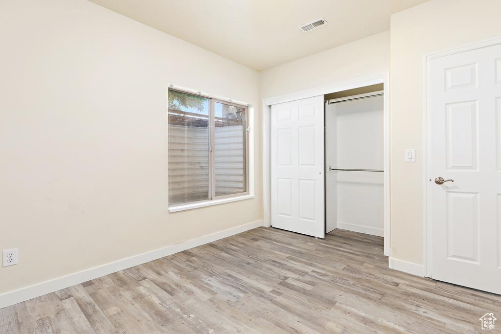 Unfurnished bedroom featuring light wood finished floors and a closet