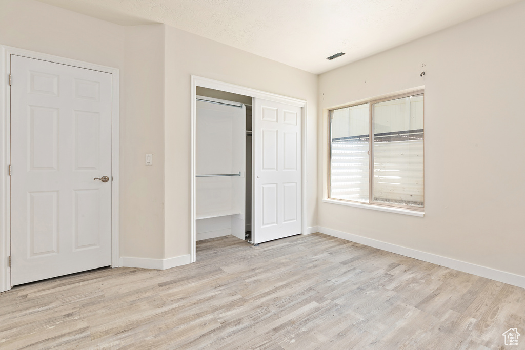 Unfurnished bedroom featuring light wood-type flooring and a closet