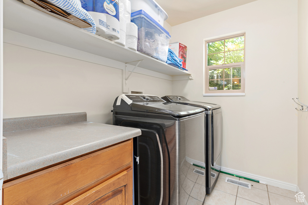 Laundry area with washer and dryer and light tile patterned floors