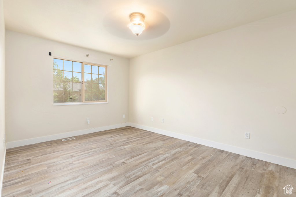 Empty room with a ceiling fan and light wood-type flooring