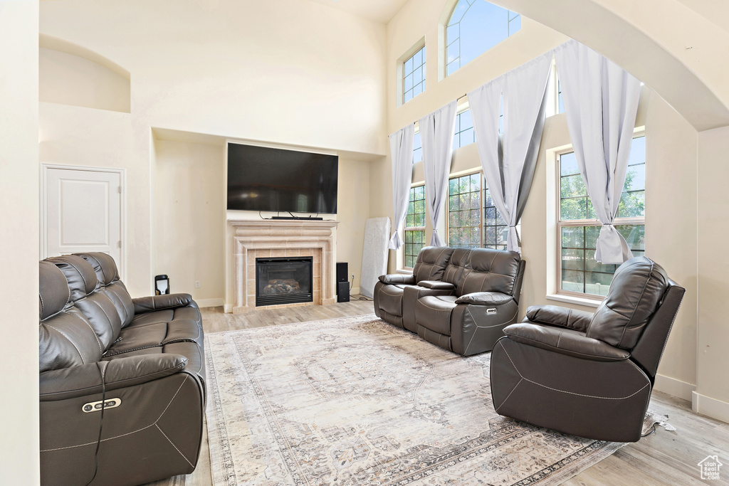 Living area featuring wood finished floors, arched walkways, a high ceiling, and a fireplace