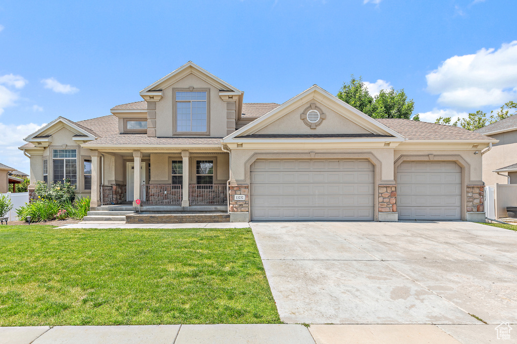 View of front of home with stucco siding, a porch, an attached garage, driveway, and a front yard