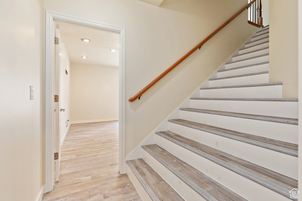 Stairway with wood finished floors and recessed lighting