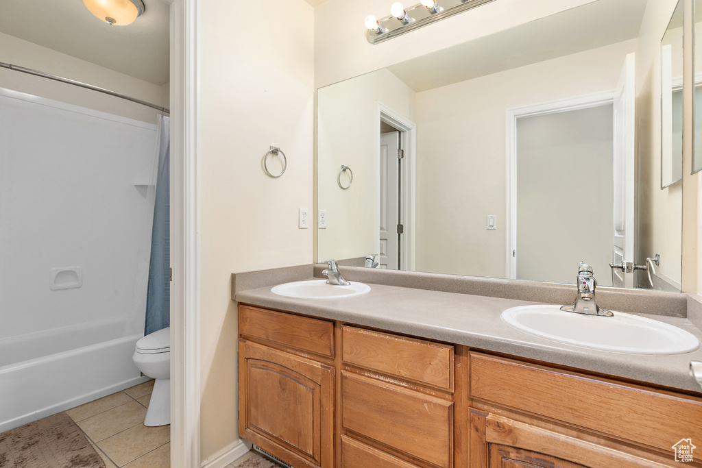 Bathroom featuring double vanity, tile patterned floors, and shower / bath combo with shower curtain