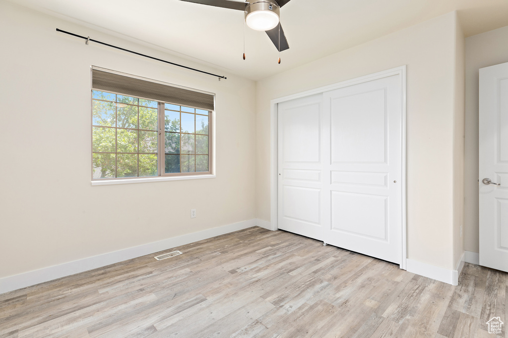 Unfurnished bedroom featuring light wood-style floors, a closet, and ceiling fan